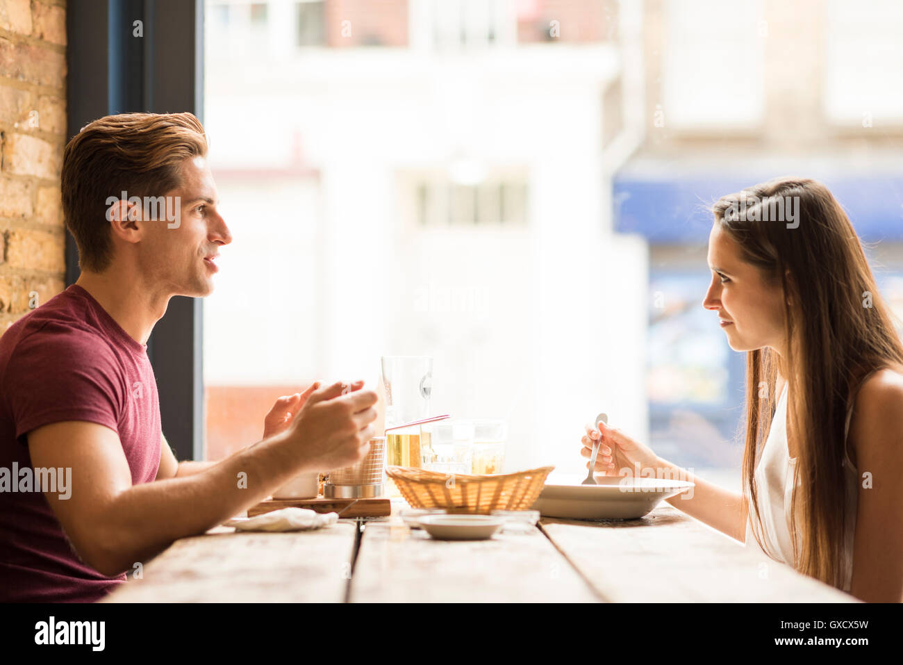 Coppia giovane chattare mentre si mangia in ristorante Foto Stock