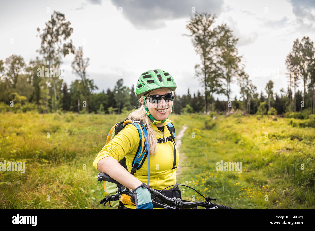 Woman mountain biker guardando la telecamera sorridendo, Augsburg, Baviera, Germania Foto Stock