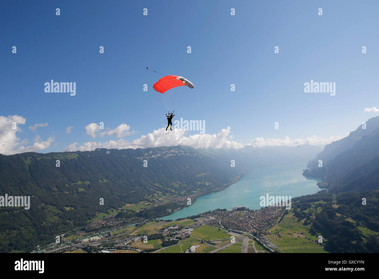 Maschio di sky diver con paracadute sopra il lago, Interlaken, Berna, Svizzera Foto Stock