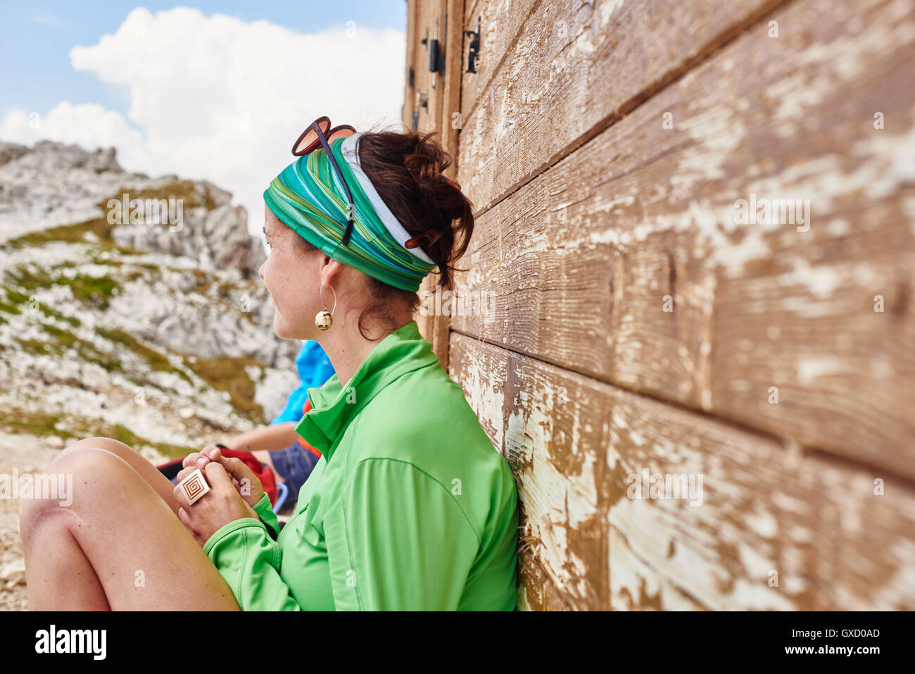 Vista laterale della donna seduta appoggiata contro la struttura in legno, Austria Foto Stock
