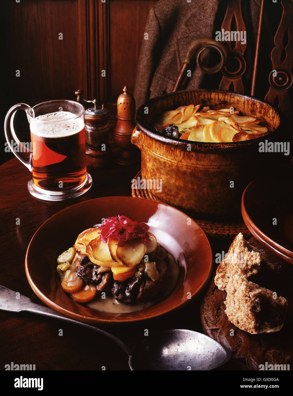 Spezzatino di cervo con cavolo rosso, tagliato a fette di patate, carote, cipolle e porri con un bicchiere di birra e di pane integrale Foto Stock