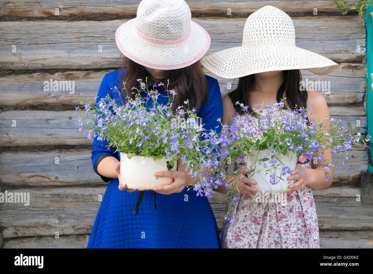 Due femmine indossando cappello da sole, azienda di piante in vaso, volti nascosti Foto Stock