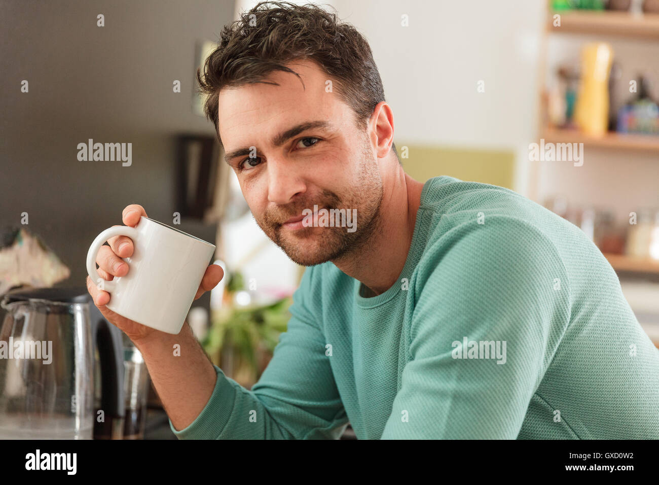 Ritratto di uomo con tazza di caffè guardando sorridente della fotocamera Foto Stock