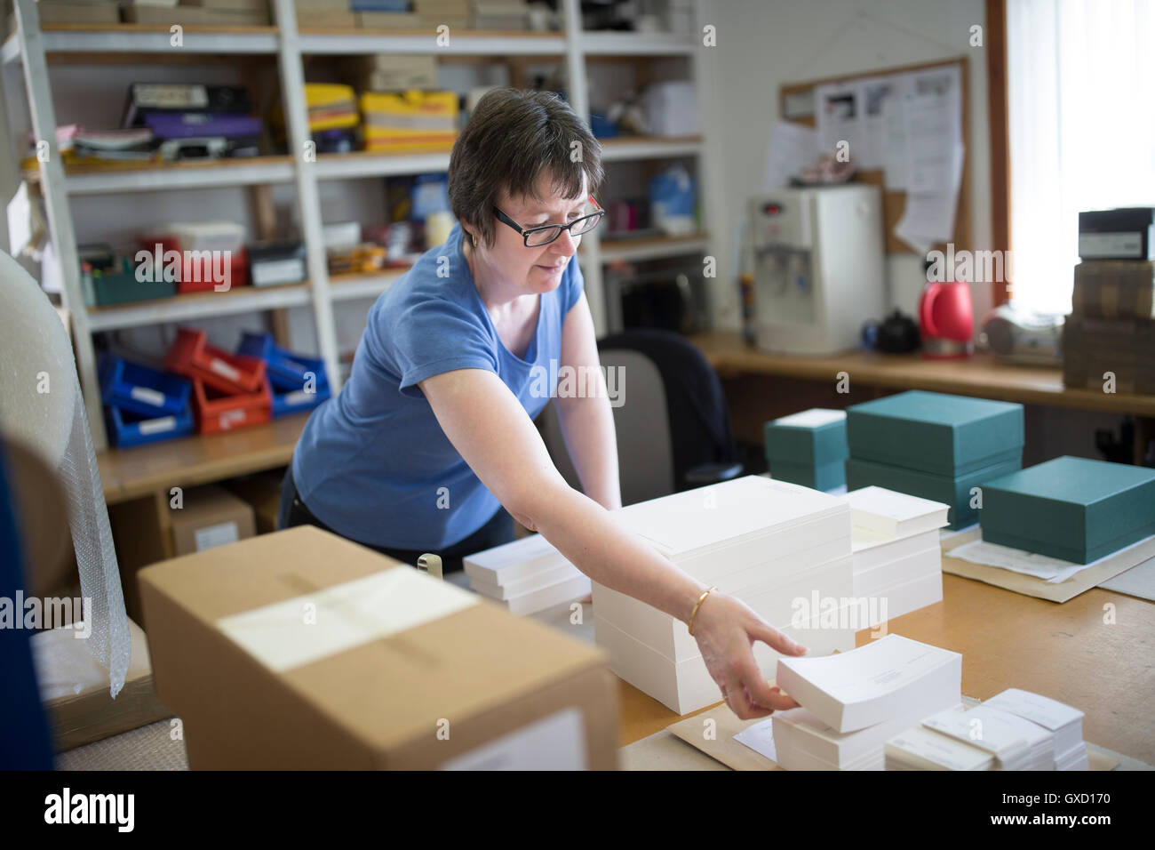 Lavoratore di sesso femminile che di imballaggio della carta impilata nella macchina da stampa workshop Foto Stock