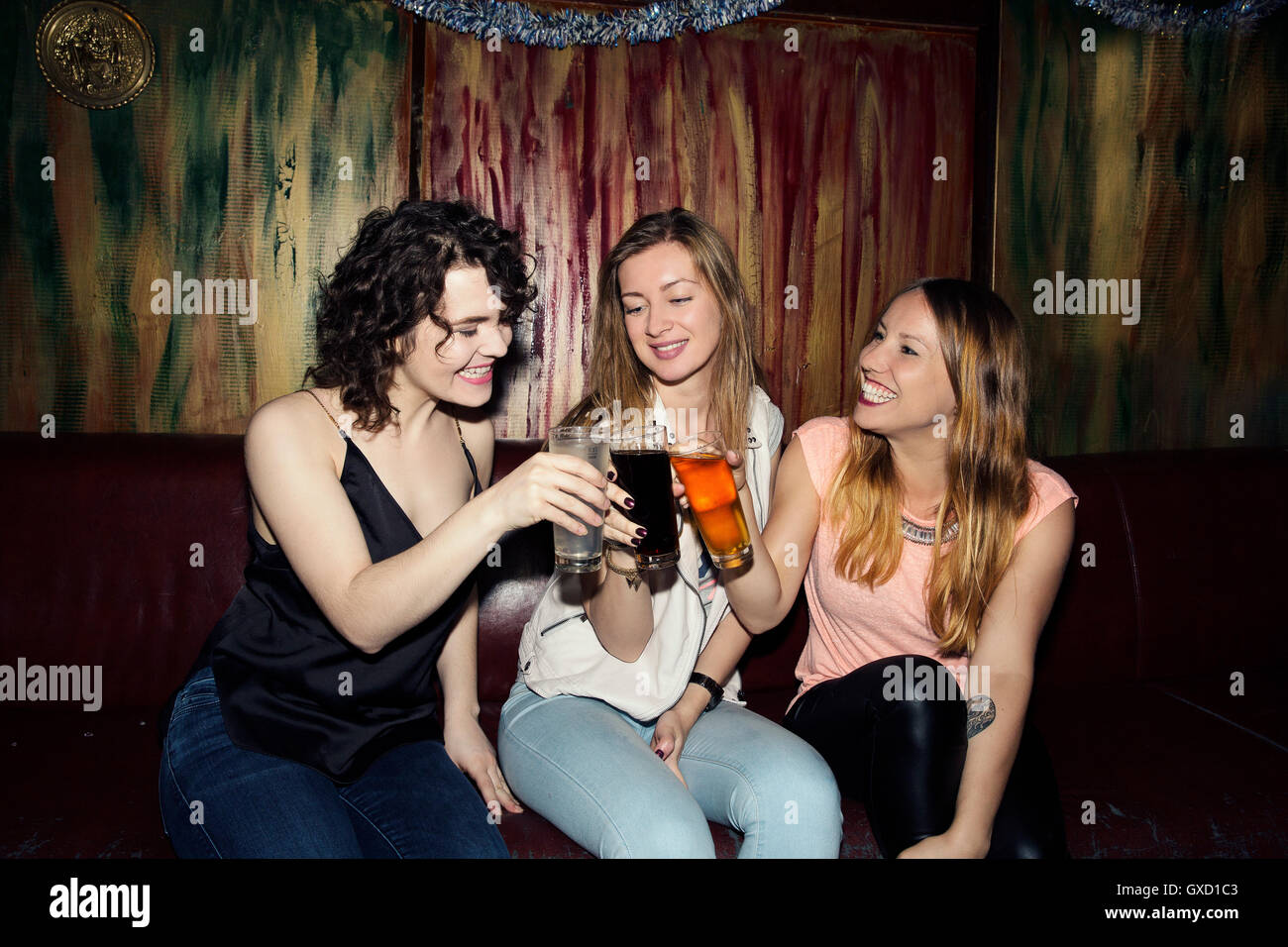 Tre femmina adulta amici sollevando un bicchiere in bar Foto Stock