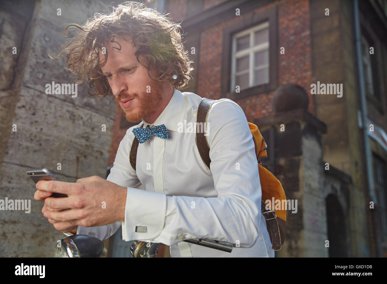 Giovane uomo all'aperto, utilizza lo smartphone, indossa una camicia e il filtro bow tie Foto Stock
