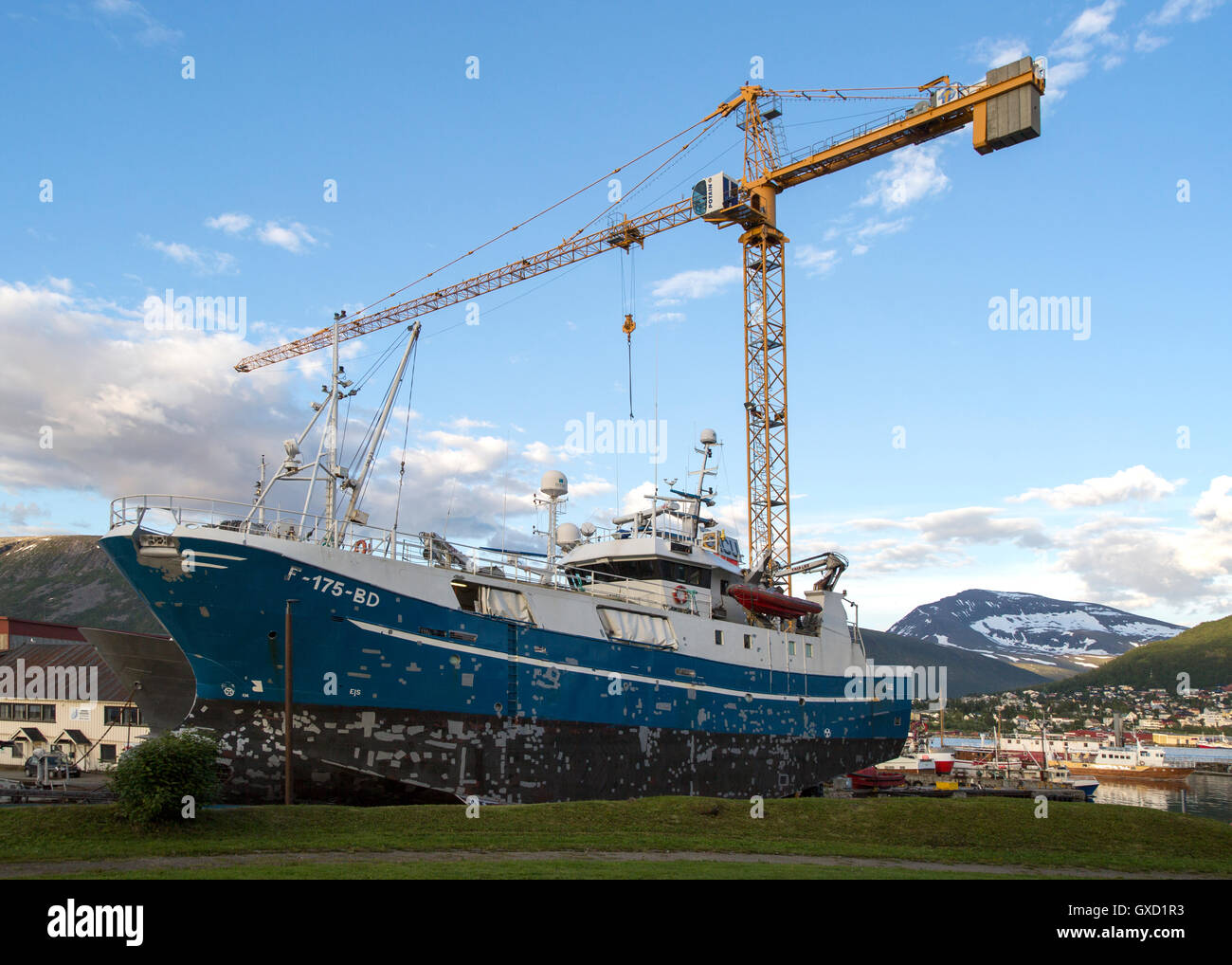 Gru da cantiere che sovrasta la pesca barca barca nel bacino di carenaggio, Tromso, Norvegia Foto Stock