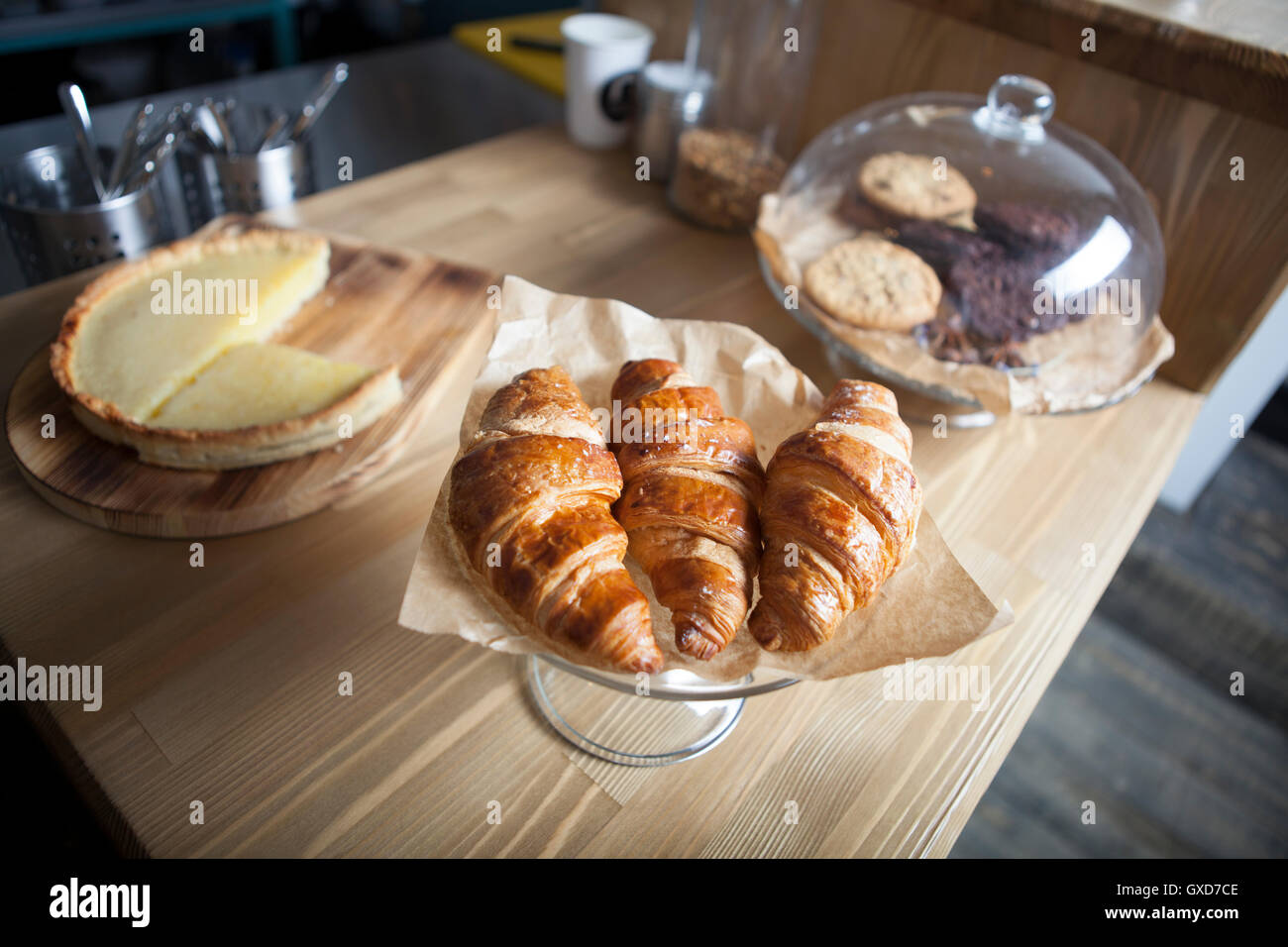 Una deliziosa colazione con croissant freschi e una fetta di torta sul vecchio sfondo di legno Foto Stock