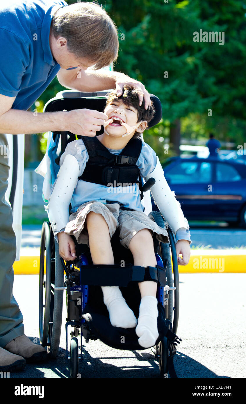 Padre aiutando bambini disabili in sedia a rotelle Foto stock - Alamy