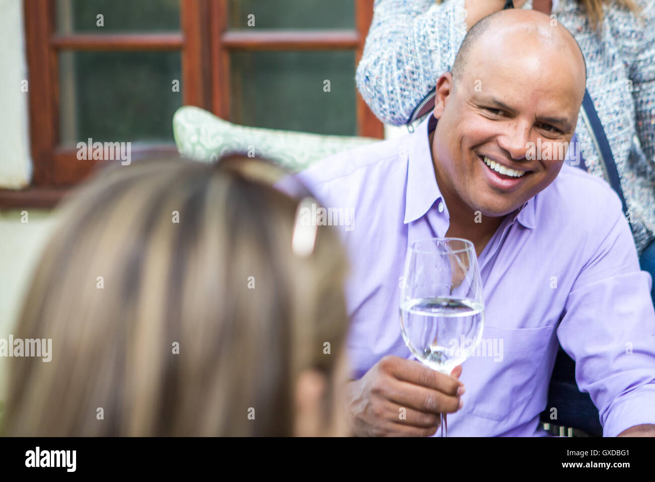 Adulti maturi in chat e ridere sul patio nel giardino partito Foto Stock