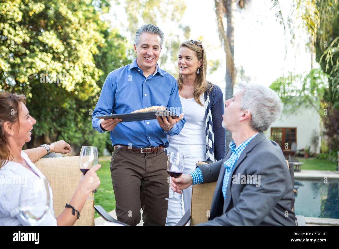 Uomo maturo che serve cucina di pesce al party in giardino Foto Stock