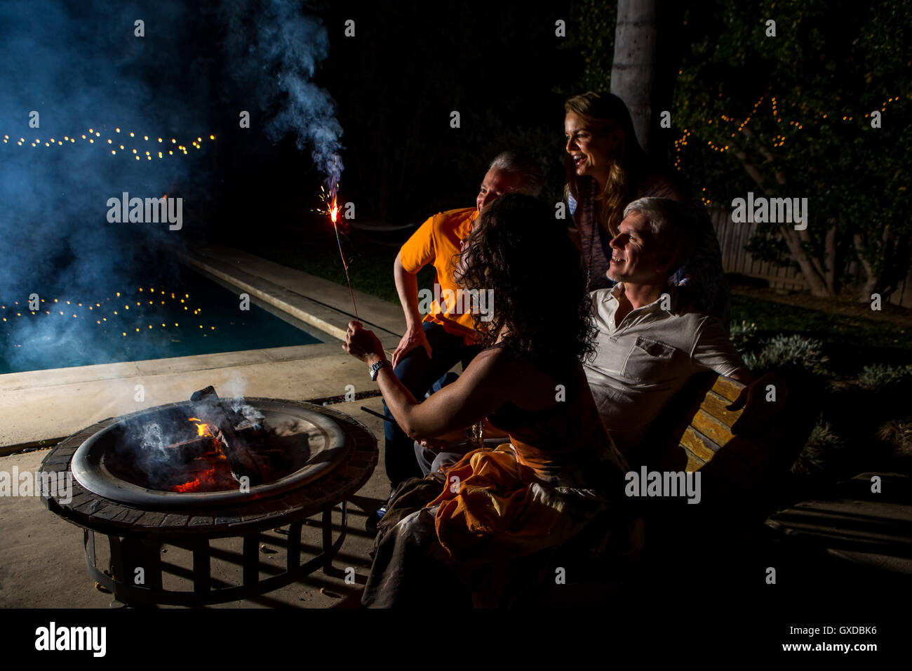 Adulto coppie guardando sparkler patio dal fuoco di notte Foto Stock