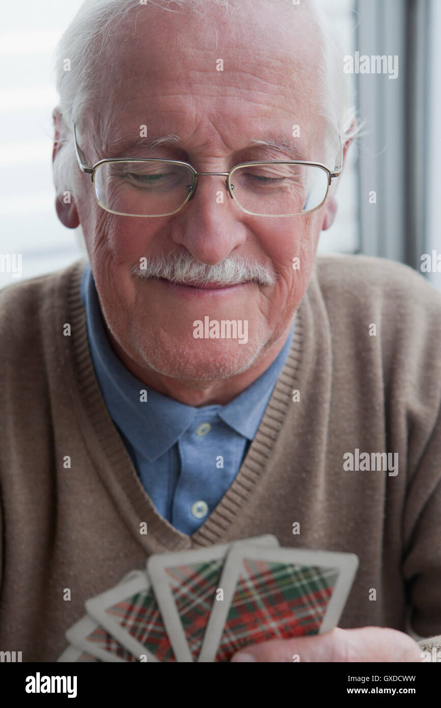 Senior uomo giocando a carte a casa Foto Stock