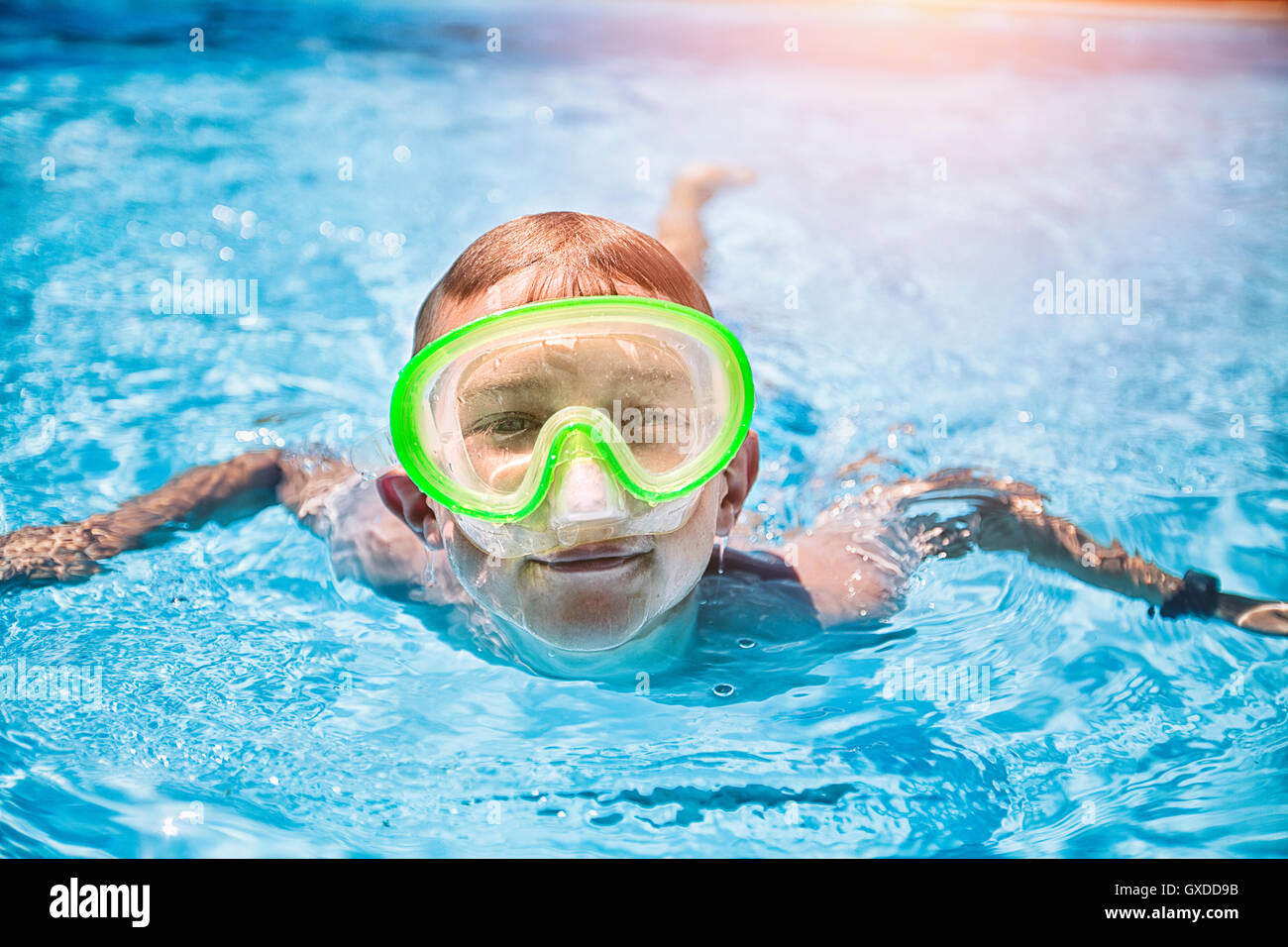 Ritratto di ragazzo che indossa il verde scuba mask nuotare nel soleggiato piscina Foto Stock