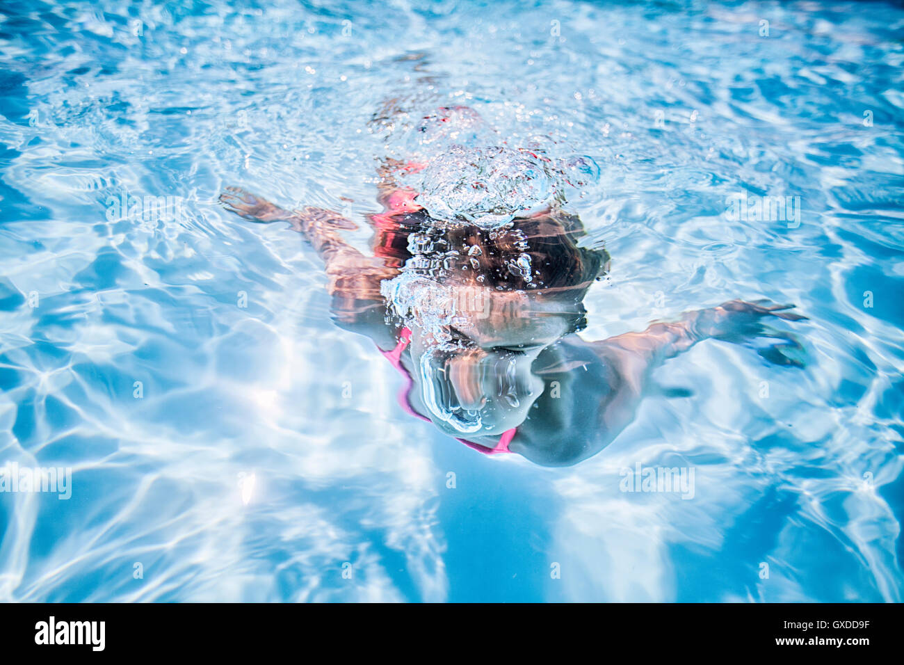 Ragazza di nuoto sott'acqua nel soleggiato piscina Foto Stock