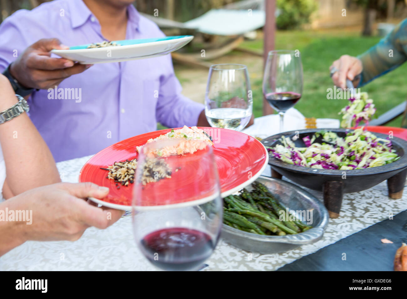 Ritagliato colpo di uomini che serve cibo su piastre a Tavolo da giardino Foto Stock