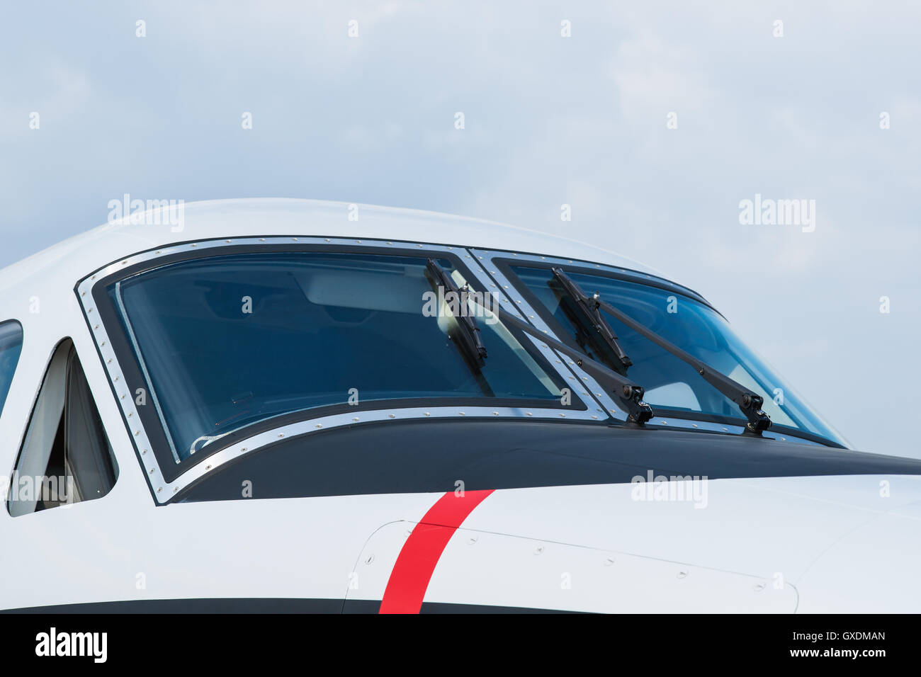 Elegante cabina di pilotaggio di un moderno velivolo di piccole dimensioni. Parabrezza e tergicristalli contro lo sfondo di colore blu pallido sky Foto Stock