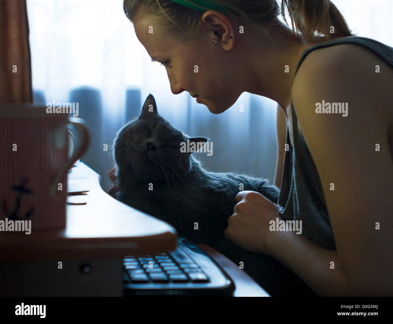 La donna caucasica petting cat al computer Foto Stock