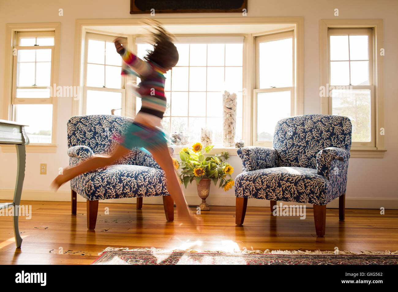 Spensierata ragazza caucasica correre e saltare nel livingroom Foto Stock
