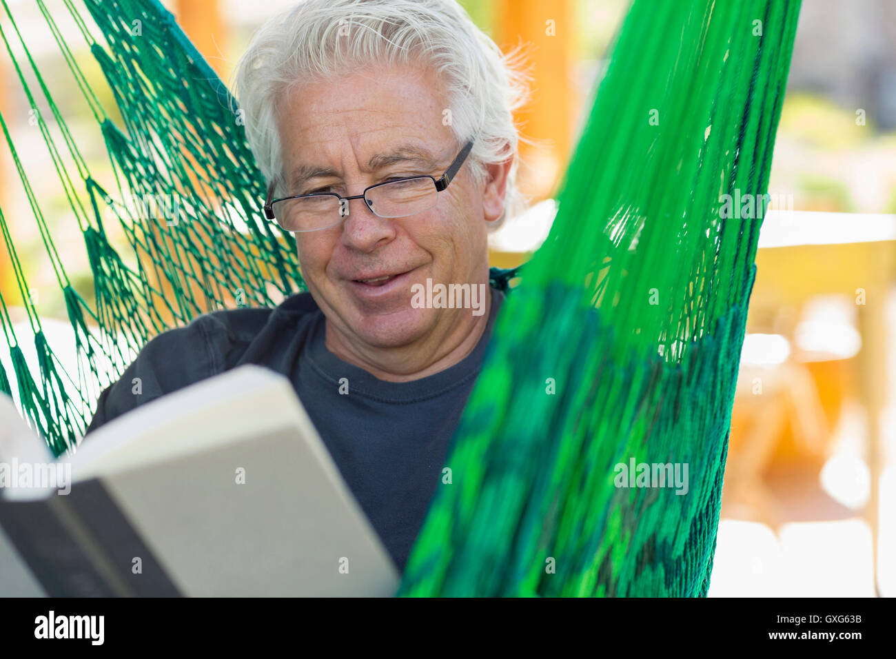 Uomo caucasico la lettura del libro verde in amaca Foto Stock