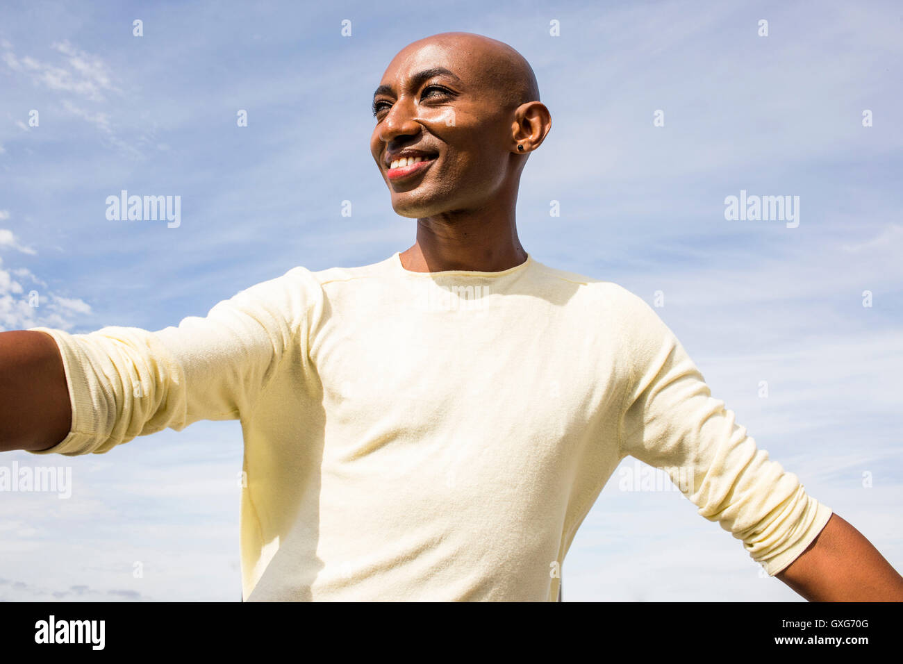 Sorridente gay uomo nero sotto il cielo nuvoloso Foto Stock