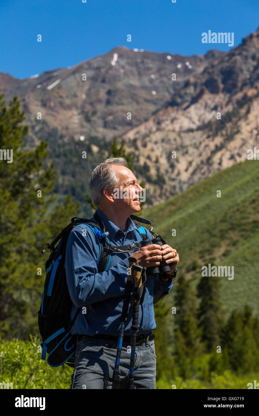 Uomo caucasico escursioni in montagna con il binocolo Foto Stock