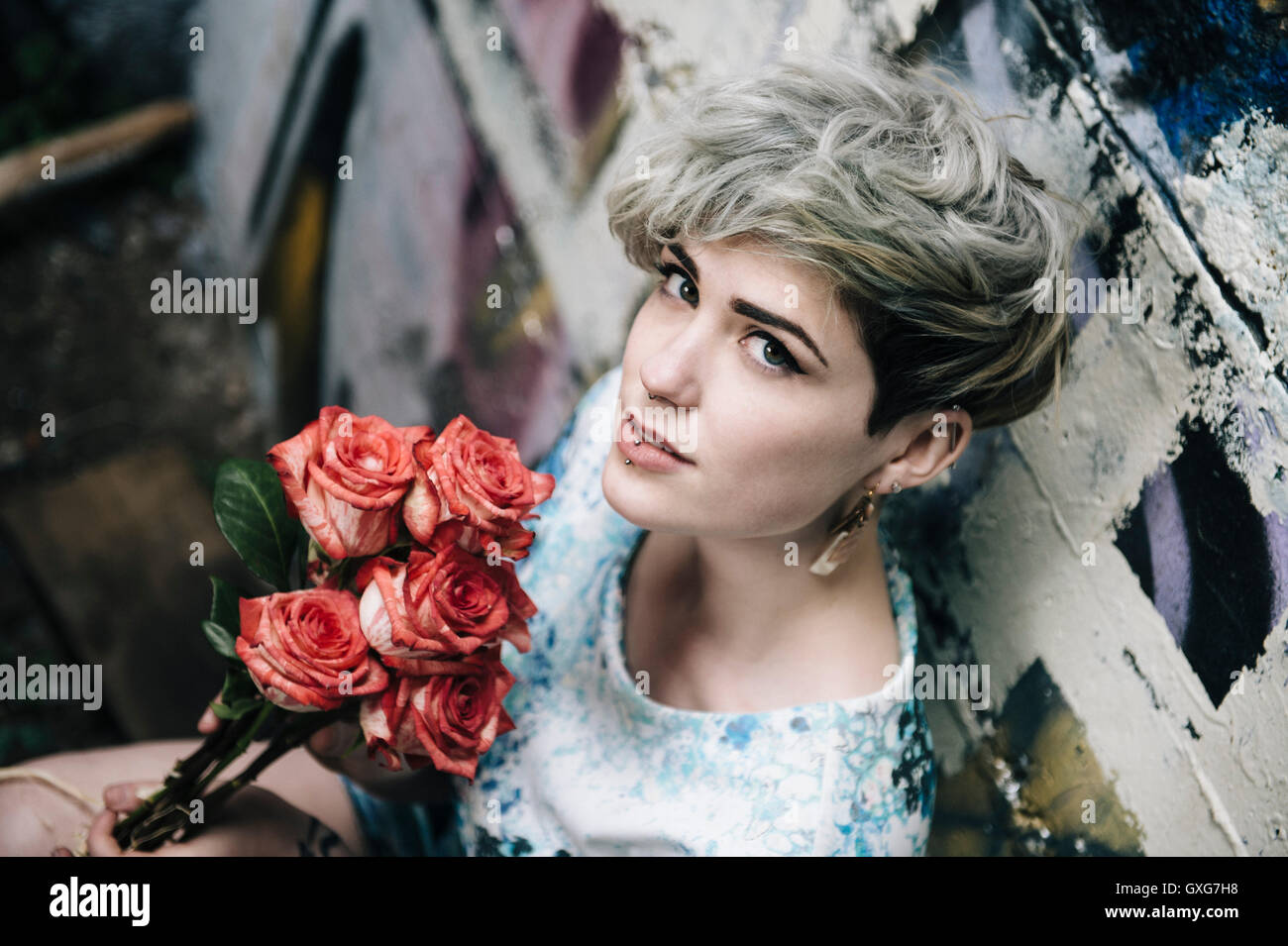 La donna caucasica al muro di graffiti holding fiori Foto Stock