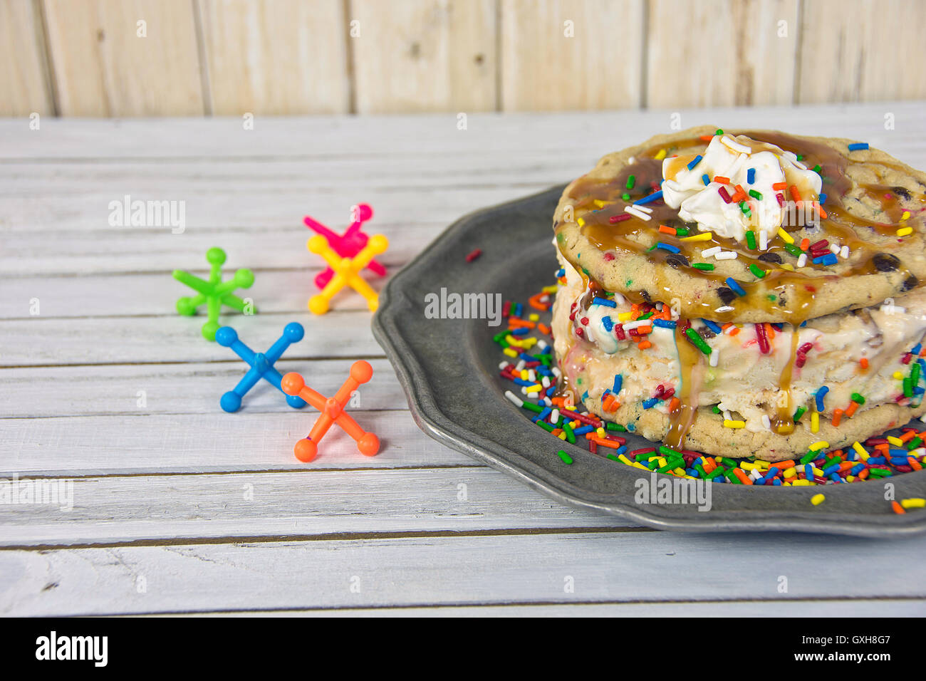 Cookie ice cream sandwich con salsa di caramello e martinetti dei giocattoli di legno Foto Stock