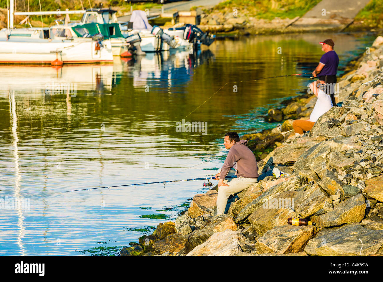 Marstrand, Svezia - 8 Settembre 2016: documentario di tre uomini di pesca in strada la sera con marina in background. Foto Stock