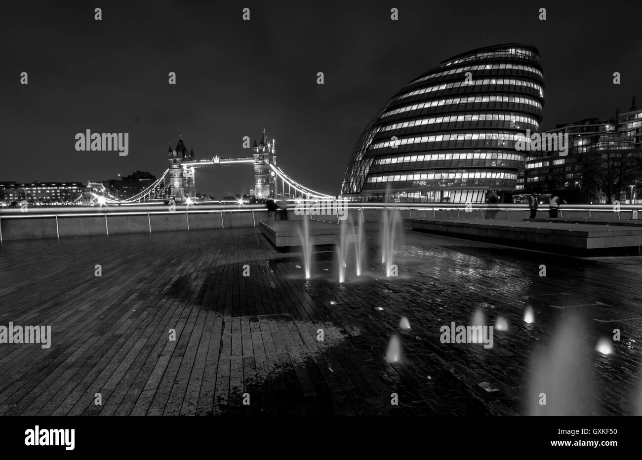 Il Tower Bridge è illuminato di notte, con il Sindaco di edificio alla sua destra, Londra, marzo convertito in bianco e nero Foto Stock
