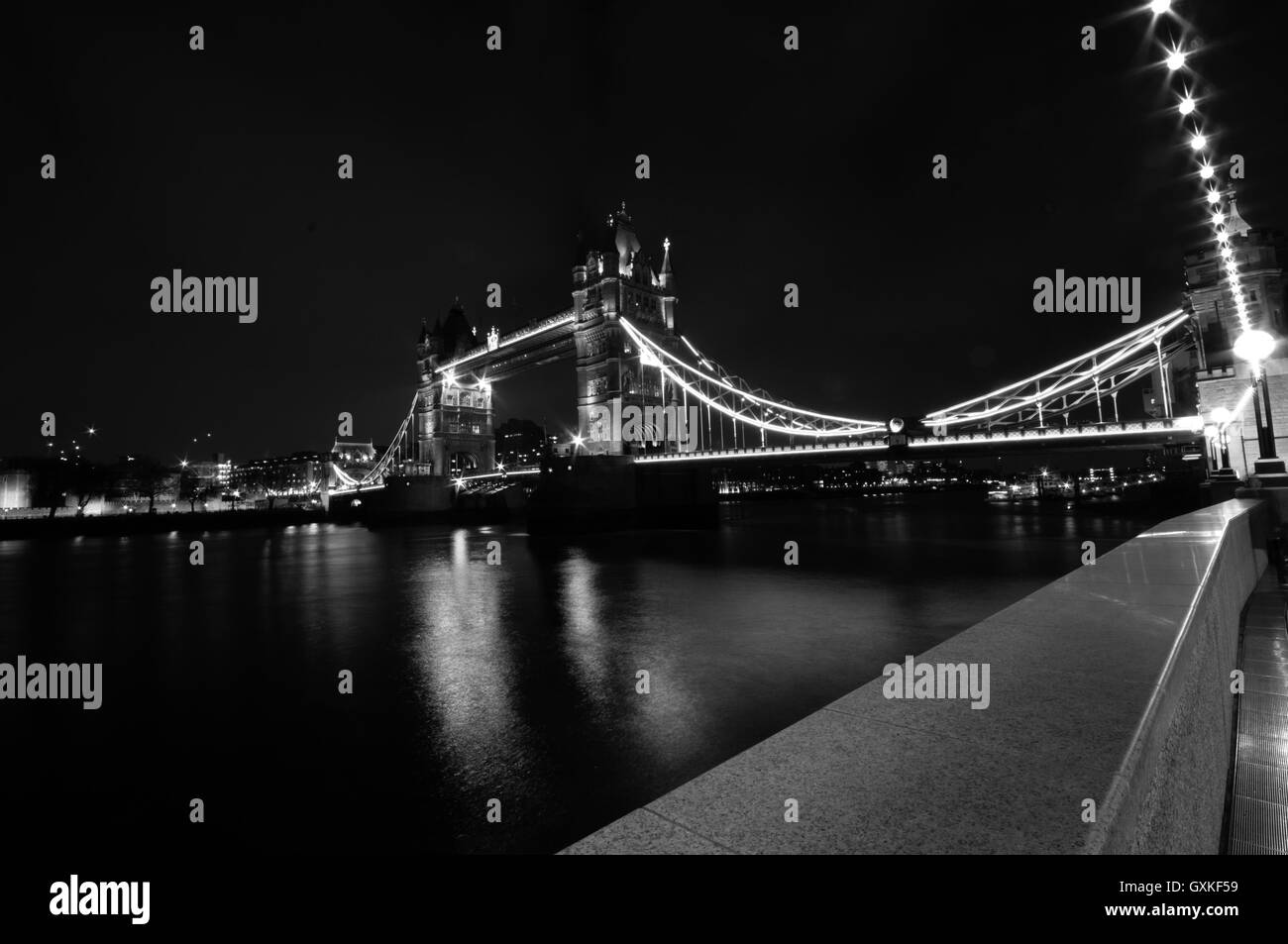 Il Tower Bridge è illuminato di notte, utilizzando una lunga esposizione a sfumare il moto del fiume Thames, London, Marzo. In bianco e nero Foto Stock