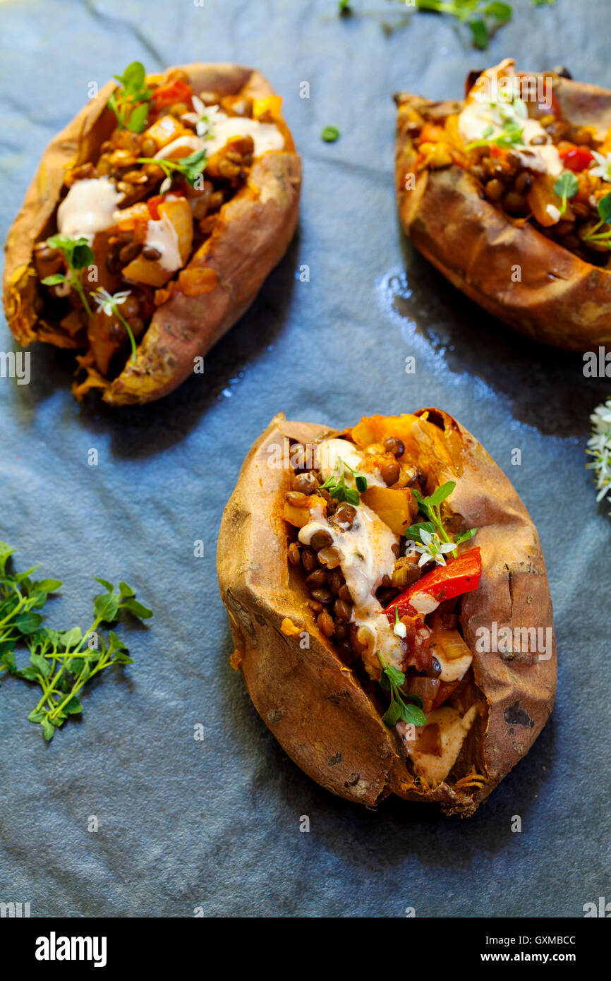 Patate dolci con il piccante di lenticchie, il peperone giallo e il riempimento di pomodoro, timo, Fiori di aglio e salsa di panna acida Foto Stock