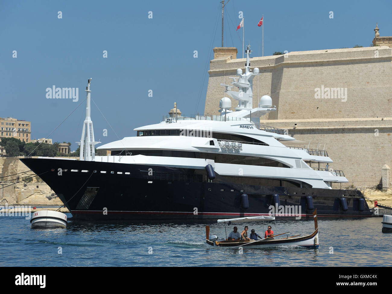 Un tradizionale Luzzu passa un lussuoso superyacht in Grand Harbour Marina, Vittoriosa, Valletta, Malta Foto Stock