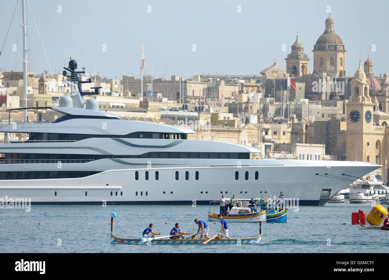 Regata di Canottaggio passato un lussuoso superyacht in Grand Harbour Marina, Vittoriosa, Valletta, Malta Foto Stock