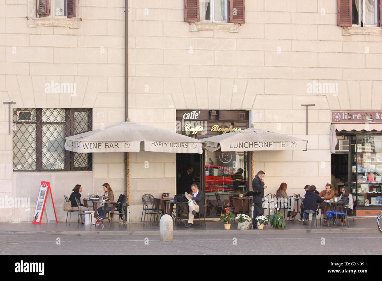 La gente seduta al di fuori di una caffetteria a Roma da una distanza, Roma, Italia Foto Stock