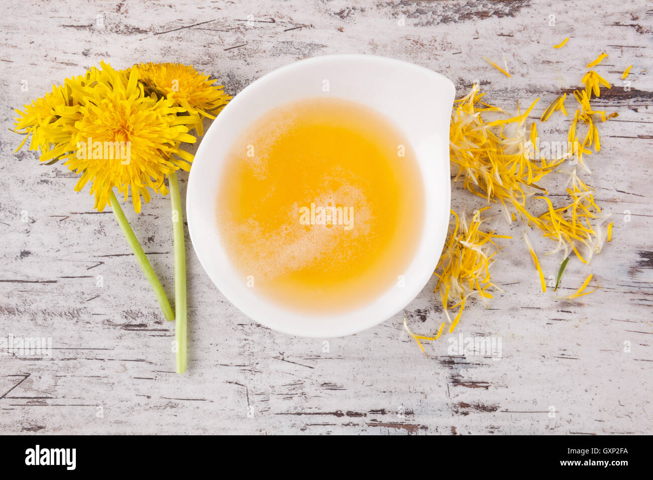 Miele di tarassaco sfondo, porre rimedio a base di erbe. Fiore di tarassaco e stelo e miele nella ciotola, vista dall'alto. Foto Stock