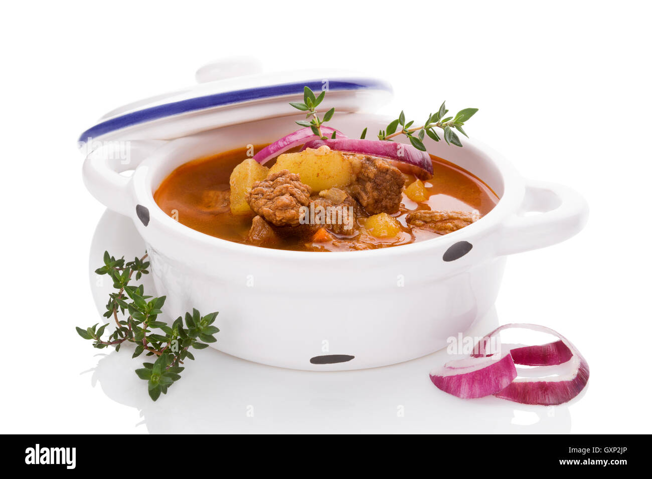 Una deliziosa zuppa di gulasch in pentola bianco su sfondo bianco. Tradizionale culinaria gulasch di mangiare. Foto Stock