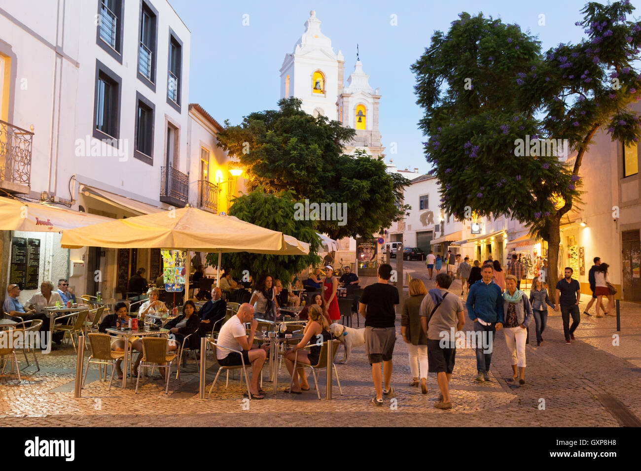 La gente seduta a un cafè all'aperto la sera presto, Lagos città vecchia, Algarve, Portogallo Europa Foto Stock