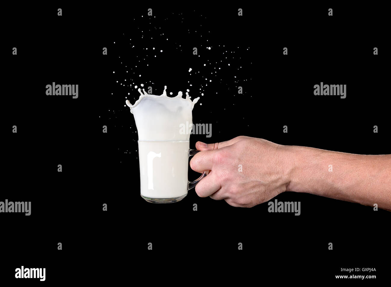 Mano umana tenendo una tazza con il latte su uno sfondo scuro Foto Stock