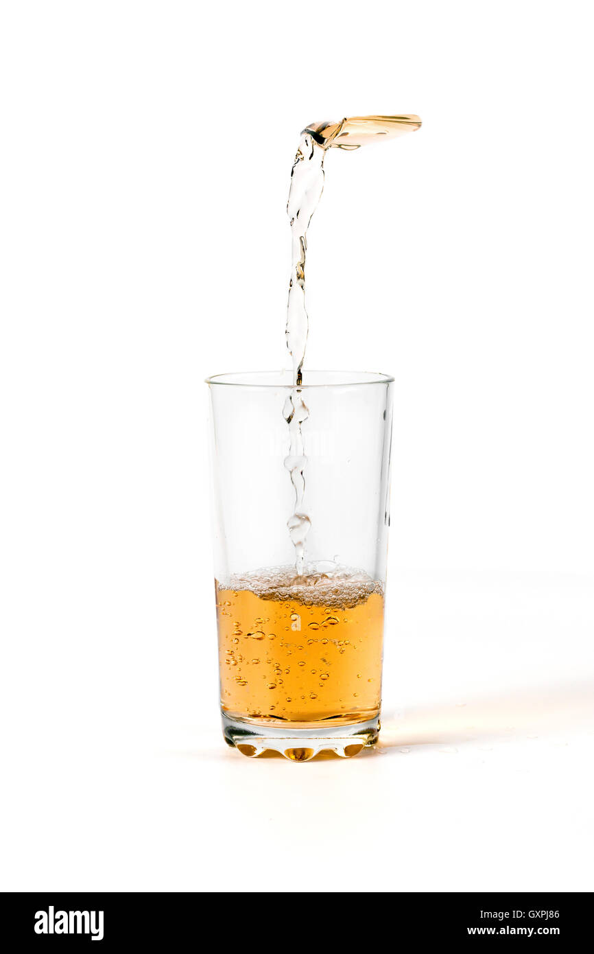 Il succo di frutta è versata in un bicchiere su sfondo bianco Foto Stock