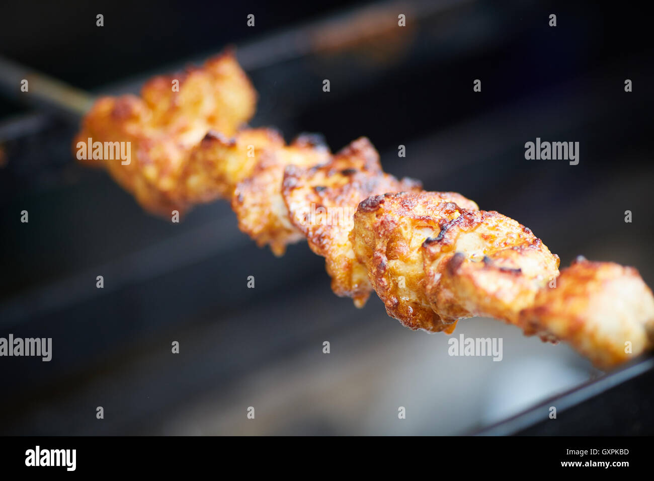 Bolton Alimentari e Drink Festival pollo Tika Kebab sul bruciatore a carbone cotta cottura barbecue esterno fatto spiedino racconto indiano via il cibo c Foto Stock