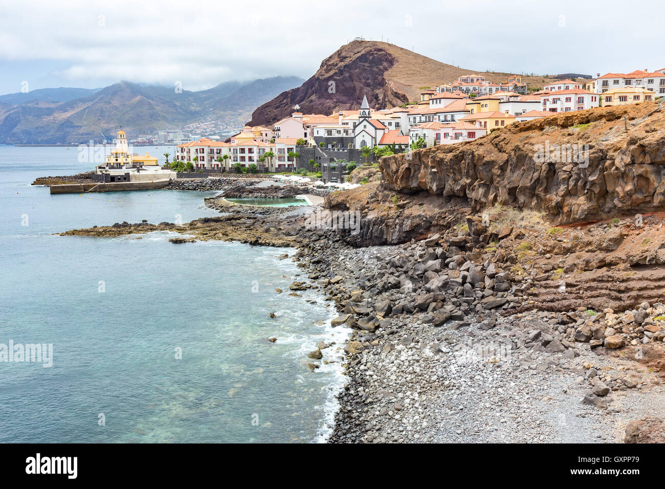 Costa in Madeira Mare con spiaggia sassosa montagne e villaggio con case Foto Stock