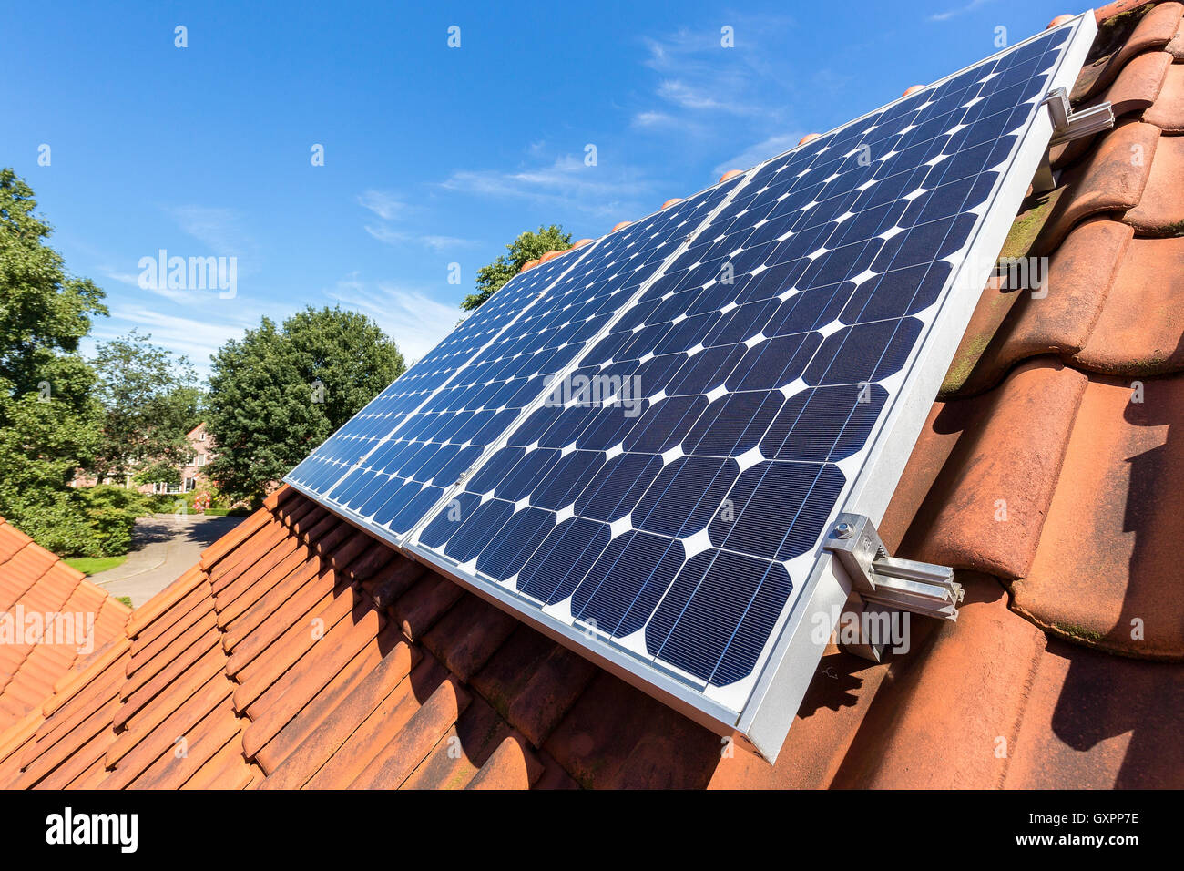 Riga blu di pannelli solari sul tetto arancione Foto Stock