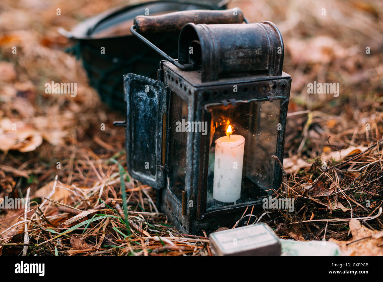 Vintage vecchia lanterna con candela che brucia sul suolo della foresta Foto Stock