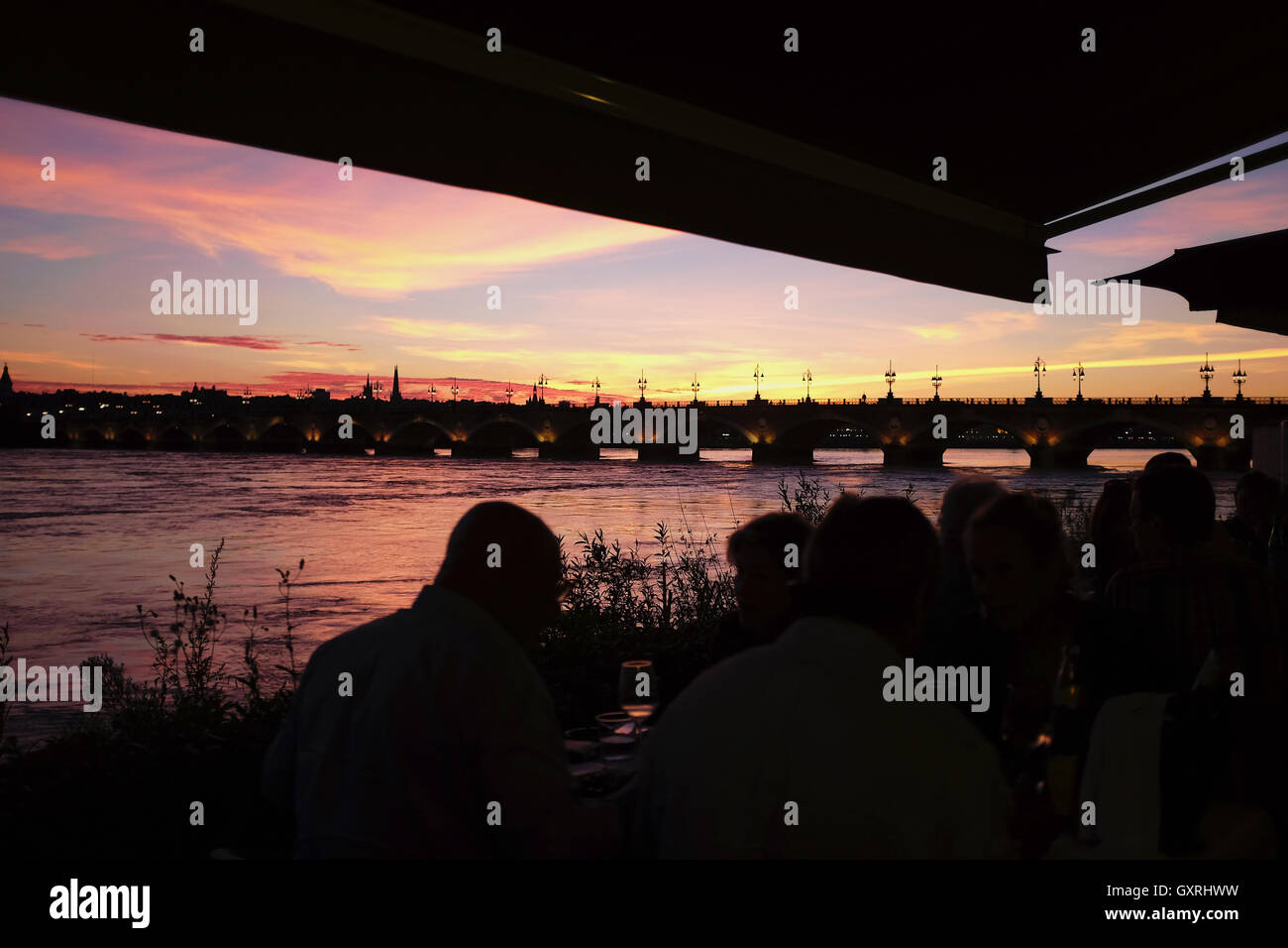 Pont de Pierre Bordeaux oltre il fiume Garonne al tramonto con persone mangiare al Cafe du Port Foto Stock