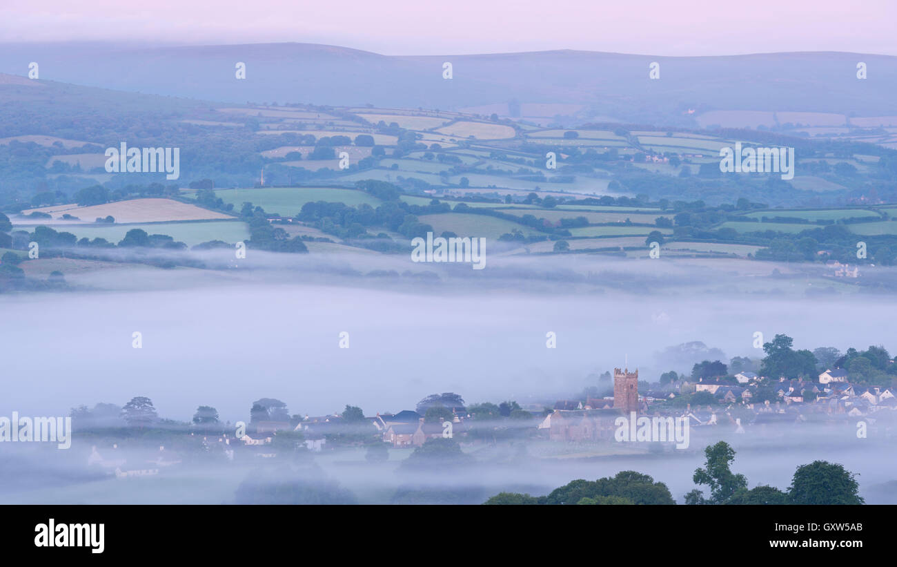 Moretonhampstead città e chiesa all'alba in una nebbiosa mattina, Parco Nazionale di Dartmoor, Devon, Inghilterra. In estate (Luglio) 2015. Foto Stock