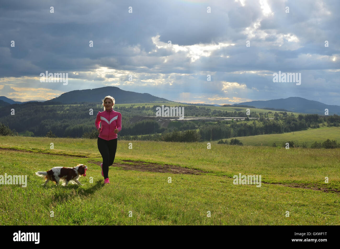 Lady in esecuzione su un prato di montagna con il suo Foto Stock