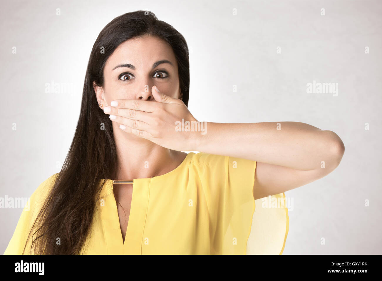 Copertura femmina la bocca con la mano, isolato in grigio Foto Stock