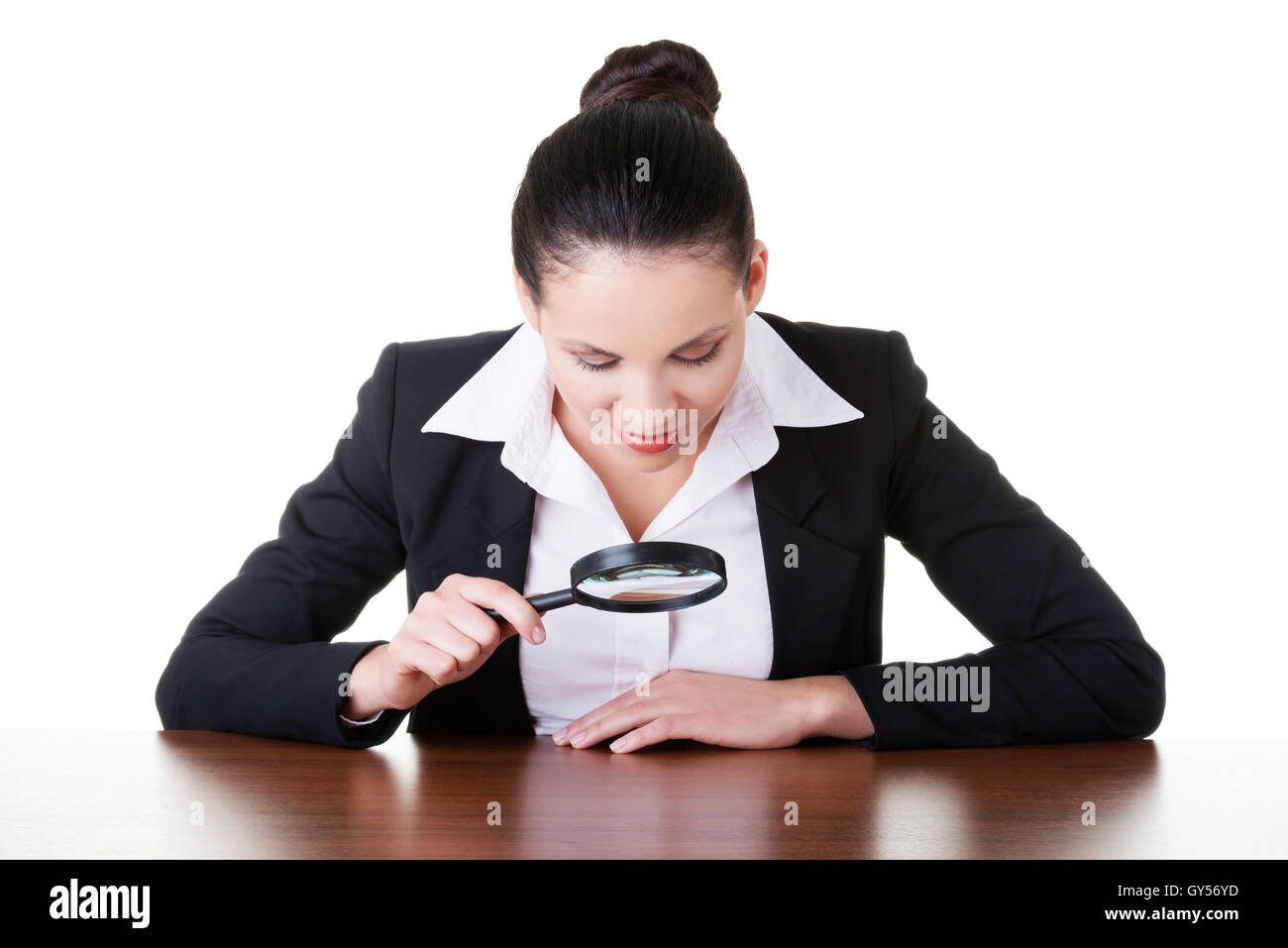 Business donna guardando attraverso la lente di ingrandimento sul tavolo. Foto Stock