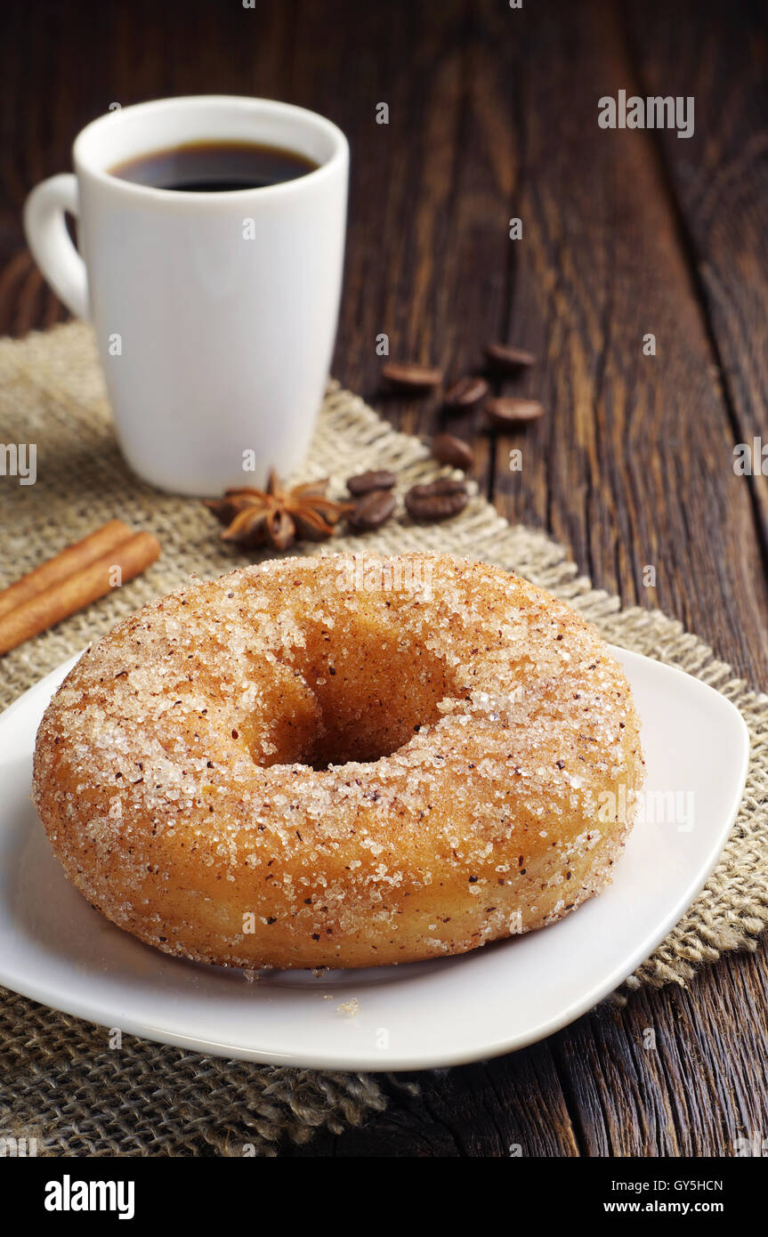 Ciambella dolce e la tazza di caffè nero scuro sul tavolo di legno Foto Stock